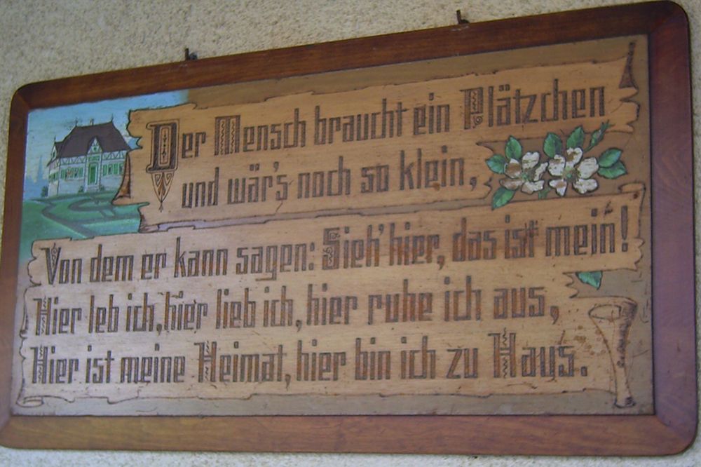 Spruchtafel: Der Mensch braucht ein Plätzchen und wär's noch so klein, von dem er kann sagen: Sieh' hier das ist mein! Hier leb ich, hier lieb ich, hier ruhe ich aus, hier ist meine Heimat, hier bin ich zu Haus.